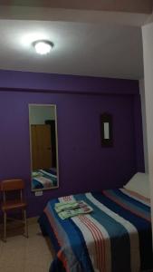 Dormitorio púrpura con cama y espejo en Tacita de Plata Apart en San Salvador de Jujuy