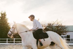 Una donna che cavalca su un cavallo bianco di Hotel Reiters Finest Family a Bad Tatzmannsdorf