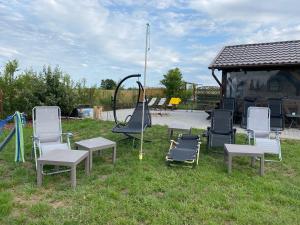 eine Gruppe Stühle und eine Schaukel im Gras in der Unterkunft Luxdomki Kąty Rybackie in Kąty Rybackie