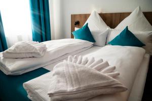 Duas camas com lençóis brancos e almofadas azuis em Hotel Hansa Stuttgart City em Estugarda