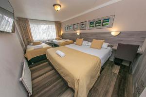 um quarto de hotel com duas camas e uma mesa em Hotel Murano em Concepción