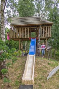 a playground with a slide and a tree house at Boerderijcamping de Berghoeve in Ruinen