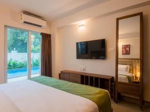 a bedroom with a bed and a mirror and a tv at Jade 4BHK Private Pool Villa by Le Pension Stays in Old Goa