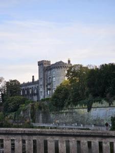 un castillo en la cima de una colina junto a un río en Cozy 2 Bedroom Apartment en Kilkenny