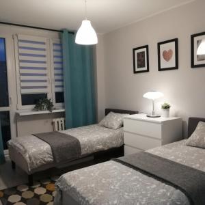 sypialnia z 2 łóżkami i stołem z lampką w obiekcie Apartament Classic Południe we Włocławku