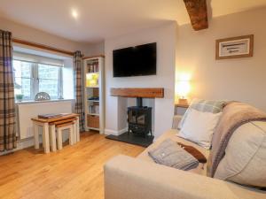 a living room with a couch and a wood stove at Clematis Cottage in Belper