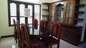 uma sala de jantar com uma mesa de vidro e cadeiras em Honey Paradise Homestay em Trivandrum