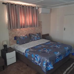 a bedroom with a bed with a blue blanket at Furnished self-catering bedsitter in Lusaka