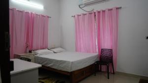 um quarto com cortinas cor-de-rosa e uma cama com uma cadeira em Honey Paradise Homestay em Trivandrum