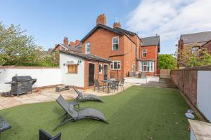 a backyard with a lawn with chairs and a grill at The Hot Tub Townhouse by Holiday Heim in Lytham St Annes