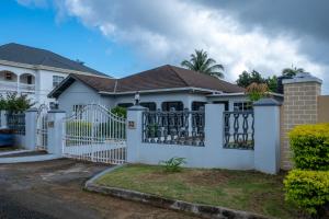 a white house with a white gate at Rustic Raspuru in St Mary