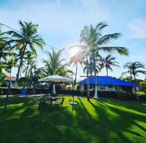 un parc avec des tables, des parasols et des palmiers dans l'établissement HOTEL CASA BLANCA, à Necoclí