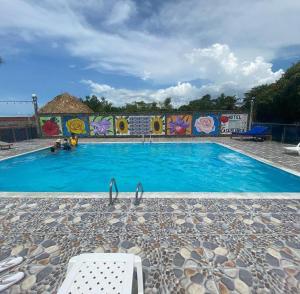 a large blue swimming pool with a wall with graffiti at HOTEL CASA BLANCA in Necoclí