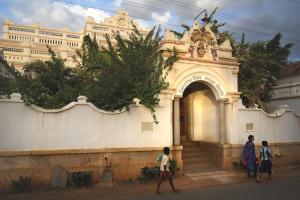 um grupo de pessoas andando em frente a um edifício em Saratha Vilas Chettinad em Kānādukāttān