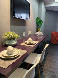 a dining room with a table with chairs and a tv at Lindo Flat Particular decorado in Brasilia