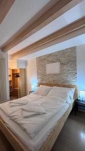 uma cama grande num quarto com uma parede de tijolos em Apartment Goldener Schnee Tesero em Tesero