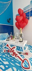 a bed with a table with red hearts and balloons at Afrodite Guest House in Caserta