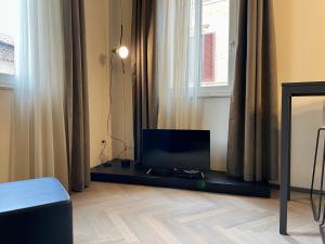 een flatscreen-tv in een kamer met een raam bij Saragozza Suite 7 Attico con altana a due passi da Piazza Grande WIFI e parcheggio gratuito in Modena