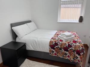 a bedroom with a bed with a blanket and a table at Luxury 2 Bed Apartment at Seymour grove in Manchester