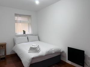 a white bedroom with a bed with towels on it at Luxury 2 Bed Apartment at Seymour grove in Manchester