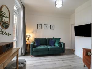 a living room with a green couch and a tv at Mabel in Whitstable