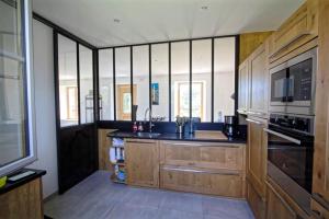eine Küche mit Holzschränken und einer Mikrowelle in der Unterkunft Villa : Les Embruns classé 4 étoiles in Bréhat