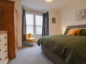 a bedroom with a bed and a chair and a window at Mabel in Whitstable