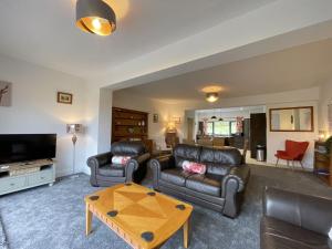 uma sala de estar com sofás de couro e uma mesa de centro em Langrigg Cottage em Portinscale