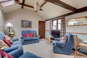 a living room with two blue chairs and a tv at Birds Farm in Colchester