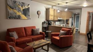 a living room with a couch and chairs and a kitchen at Condo du Bonheur in Mont-Tremblant