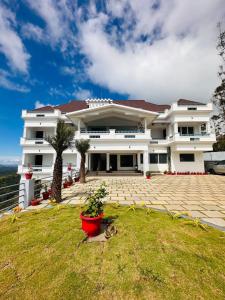 a large white building with a lawn in front of it at The Windy Mist Resort Munnar in Chinnakanal