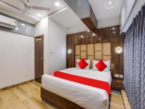 1 dormitorio con 1 cama grande con almohadas rojas en OYO Hotel bhanu Villa, en Ahmedabad