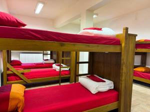 a room with four bunk beds with red sheets at Rifugio Nido del Biancone in Bosio