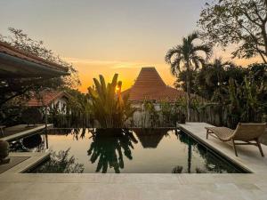 a swimming pool with a chair next to a house at Joglo Villas Uluwatu - Tropical Oasis in Uluwatu