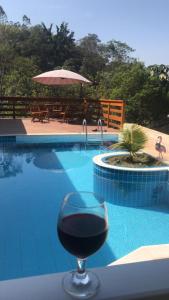 um copo de vinho sentado numa mesa ao lado de uma piscina em Chácara Morada de Cristo em Igaratá