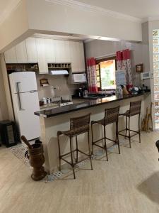uma cozinha com um balcão com cadeiras e um frigorífico em Chácara Morada de Cristo em Igaratá