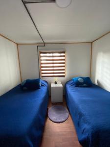 2 camas en una habitación pequeña con ventana en Cabaña centro Frutillar Alto, en Llanquihue