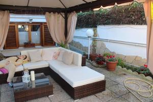 eine weiße Couch unter einem Schirm auf einer Terrasse in der Unterkunft Villa Severino Ferrari Anzio in Anzio