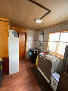 una pequeña cocina con fregadero y nevera. en Cabaña centro Frutillar Alto, en Llanquihue