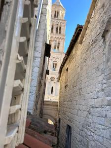 um beco com uma torre de relógio ao fundo em Largo apartment in the heart of Diocletian palace em Split