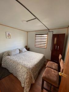 a bedroom with a bed and a chair and a window at Cabaña centro Frutillar Alto in Llanquihue