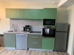 een keuken met groene en witte kasten en apparaten bij Appartement Torii - Maulévrier Cholet Puy du Fou in Maulévrier