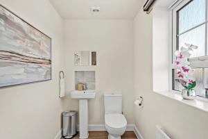 a white bathroom with a toilet and a window at Stunning 4 bed In Leicester with Garden & Parking! in Leicester