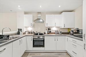 una cocina blanca con armarios blancos y fregadero en Stunning 4 bed In Leicester with Garden & Parking!, en Leicester
