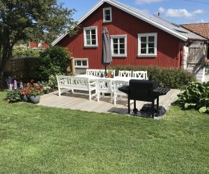 a red house with a wooden deck with a piano at Rovor och Rum Lägenhet Rännet in Skärhamn