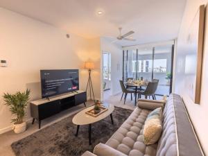 uma sala de estar com um sofá e uma televisão de ecrã plano em Toowong Central Carpark and Wifi Great value 1BR Apt em Brisbane