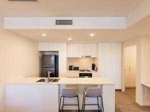 a kitchen with white cabinets and a kitchen island with two chairs at Toowong Central Carpark and Wifi Great value 1BR Apt in Brisbane