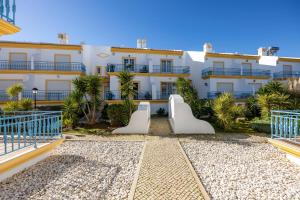 Un gran edificio blanco con palmeras delante. en Vila Hortense, en Alvor