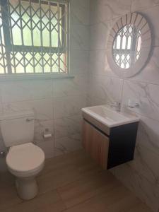 a bathroom with a toilet and a sink and a window at Vaal Haven - riverside getaway in Vanderbijlpark