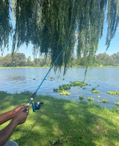 a person holding onto a fishing pole in front of a lake at Vaal Haven - riverside getaway in Vanderbijlpark